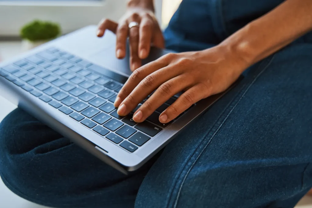 Person arbeitet mit einem Laptop auf dem Schoß